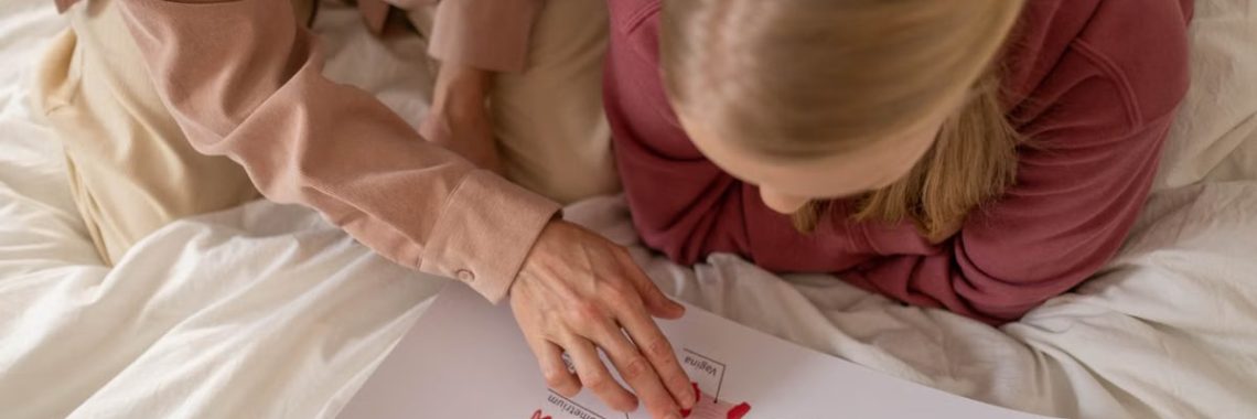 Mother and daughter studying reproductive system illustration for sex education at home.