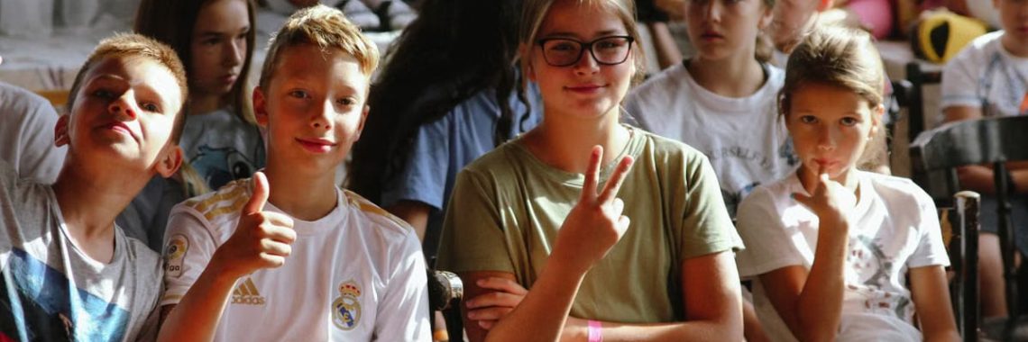 Cheerful group of children sitting together at an indoor event, showcasing friendships and diversity.